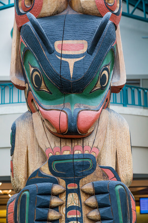 Traditional Colorful Totem Pole with Modern Building in Backgroundの写真素材