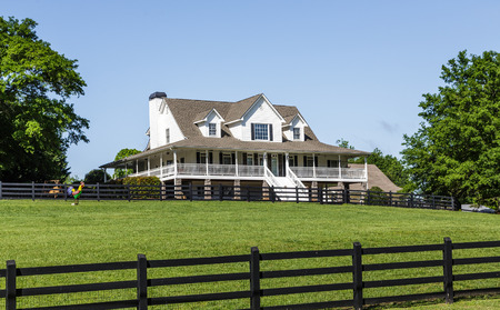 Traditional House Beyond Green Lawn and Black Fence Under Blue Skyの写真素材