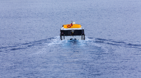 Yellow and White Lifeboat Cutting Through Blue Water in Harborの写真素材