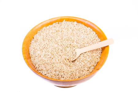 Nutritious, Whole-Grain Brown Rice in a Wood Bowl on White Background with Wood Spoonの写真素材