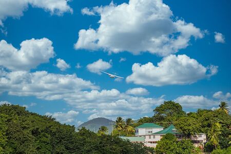 A twin propeller plane taking off over a tropical paradiseの写真素材