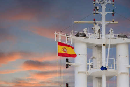 The flag of Spain flying on the tower of a  white cruise shipの写真素材