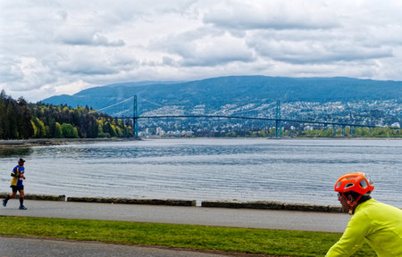 Cyclist and Runner in Stanley Park with Lions Gate Bridgeのeditorial素材