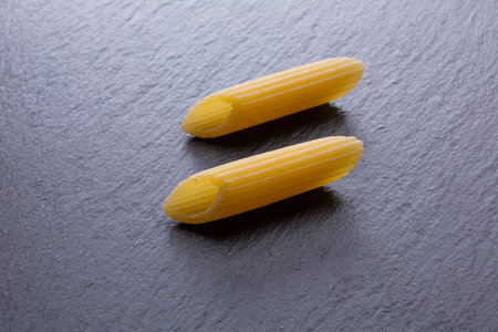 close up of a raw italian penne pasta on black slateの写真素材