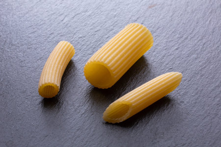 close up of a raw italian penne pasta on black background