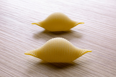 Close-up of uncooked conchiglie pasta on wooden backgroundの写真素材