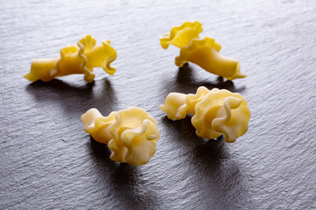 Uncooked Italian pasta on a black slate background. Selective focus.の写真素材