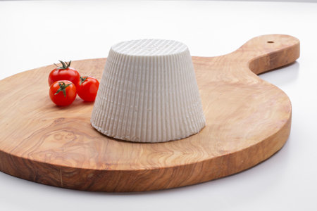 cottage cheese with cherry tomatoes on a wooden cutting board with a white backgroundの写真素材