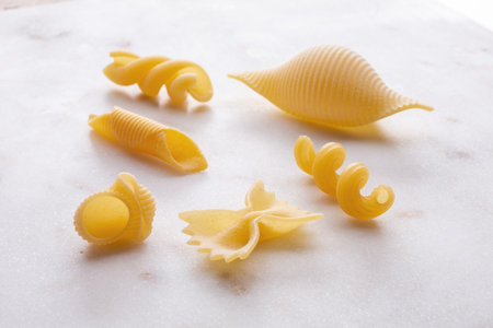 Variety of types and shapes of Italian pasta on a marble boardの写真素材