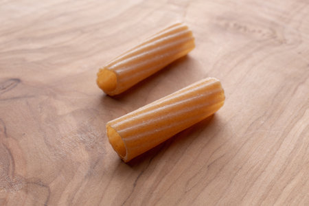 Closeup of two uncooked pasta on a wooden cutting board.の写真素材