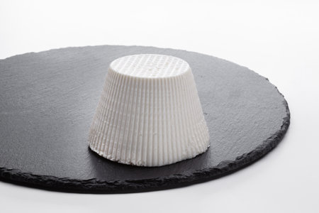 fresh cottage cheese on a round slate with a white backgroundの写真素材