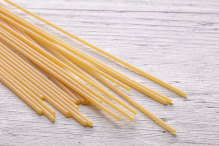 Uncooked spaghetti on a white wooden background. Selective focus.の写真素材