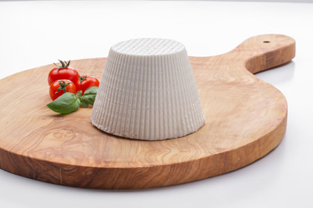 cottage cheese with cherry tomatoes and basil leaf on a wooden cutting board with a white backgroundの写真素材
