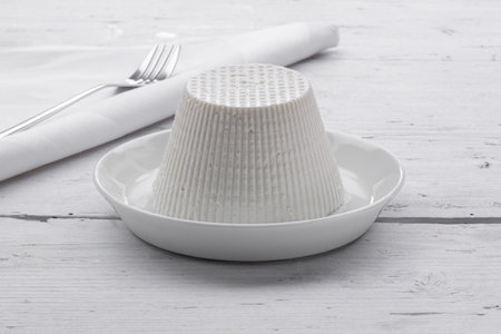 Cottage cheese on white plate with fork and napkin on wooden tableの写真素材