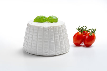 fresh Italian soft ricotta cheese served with red tomatoes and basil isolated on white backgroundの写真素材