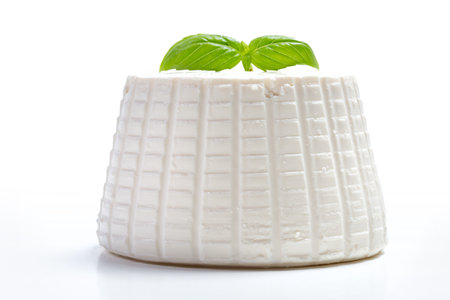 whole fresh ricotta cheese on a white background and basil leafの写真素材