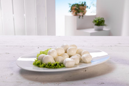 Mozzarella cheese balls with salad in a plate on a white wooden tableの写真素材