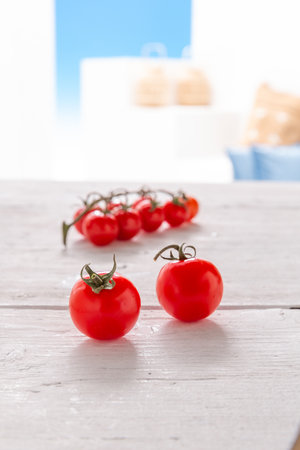 Fresh cherry tomatoes on wooden table with blurred kitchen in the background.の写真素材