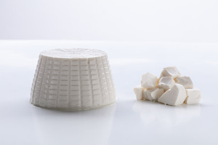 Whole and crumbled ricotta cheese on a white backgroundの写真素材