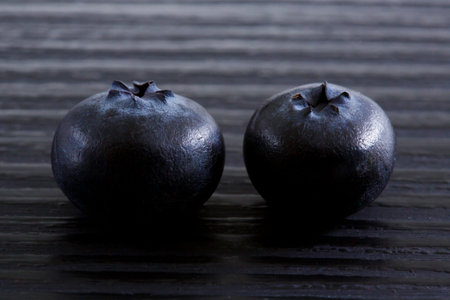 Two fresh blueberries on a black wooden background. close up.の写真素材