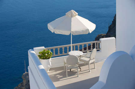 Two chairs under umbrella with the sea vie in Oia, Santorini island, Greece.の写真素材