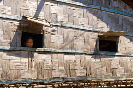 Bandarban, Bangladesh, February 20, 2014 - Woman looks from the windows of the traditional Marma hill tribe house in Bandarban, Bangladesh.のeditorial素材