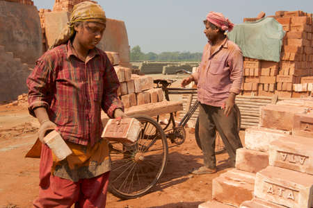 Dhaka, Bangladesh, February 19, 2014 - Two workers move bricks at a factory in Dhaka, Bangladesh. In Bangladesh women often attend very hard jobs.のeditorial素材