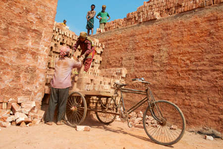 Dhaka, Bangladesh, February 19, 2014 - Two workers load bicycle with bricks in Dhaka, Bangladesh....