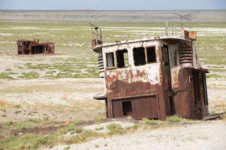 Rusted remains of fishing boats at the sea bed of the Aral sea, Aralsk, Kazakhstan. Evaporation of formerly one of four largest lakes in the world is considered one of the planetの写真素材