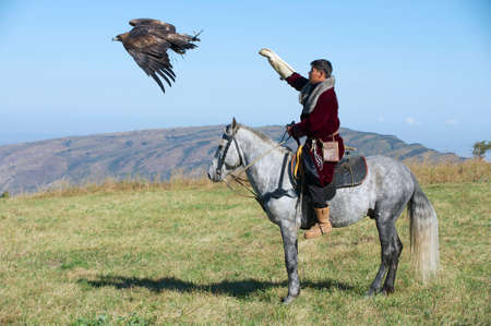 Circa Almaty, Kazakhstan, September 18, 2011 - Mongolian hunter launches golden eagle to pursue prey...