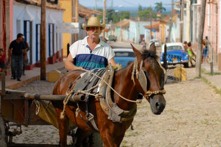 Trinidad, Cuba, October 30, 2006 - Man drives horse driven carriage at the street of Trinidad town in Trinidad, Cuba. Town of Trinidad in Cuba is a UNESCO World Heritage site.のeditorial素材