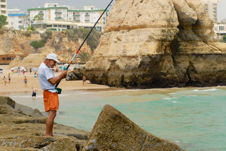 Portimao, Portugal, July 18, 2006 - Man does fishing at Praia da Rocha beach in Portimao, Portugal.のeditorial素材