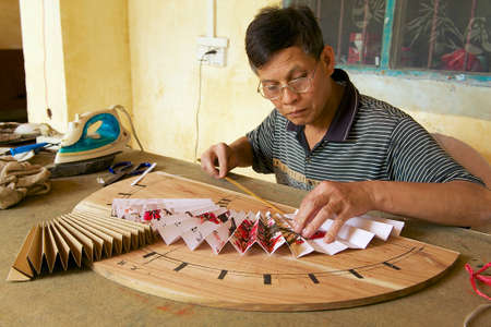 Yangshuo, China - May 04, 2009 - Man produces traditional Chinese fan in Yangshuo, China. Yangshuo town is famous in Guangxi region of China for itのeditorial素材