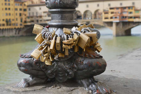 Florence Italy March January 2007: Padlocks locked at the Arno river bank with Ponte Vecchio bridge at the background in Florence Italy.のeditorial素材