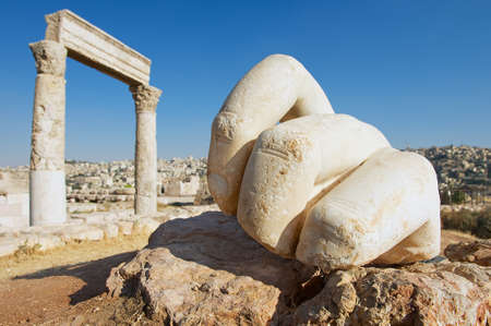 Stone Hercules hand at the antique Citadel in Amman, Jordan. At the background: ruins of the Hercules temple and Amman city.の写真素材