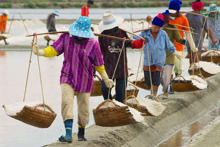 Huahin, Thailand, May 13, 2008 - People carry salt at the salt farm in Huahin, Thailand. Salt production is one of the main industries in Huahin area, it brings modest income to many local families.のeditorial素材
