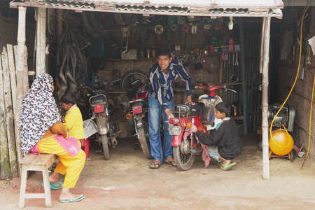 Puthia, Bangladesh, February 16, 2014 - People fix motorbike in a workshop in Puthia, Bangladesh.のeditorial素材