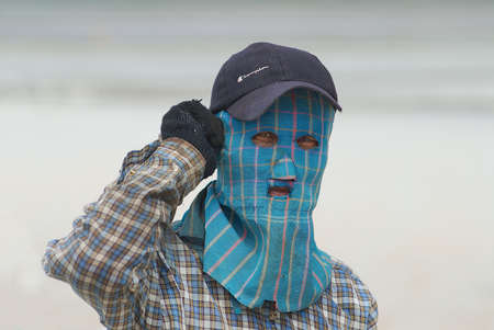 Huahin, Thailand, May 13, 2008 - Portrait of a man wearing face mask at the salt farm in Huahin, Thailand. Combination of heat, sunshine and salt makes salt farming job very hard.のeditorial素材
