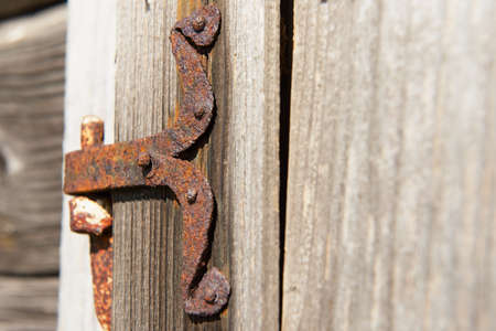 Vintage rusted metal door hinge over the weathered wooden wall.の写真素材