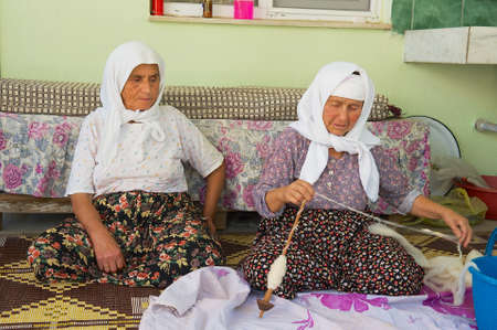 Karacahisar, Turkey, August 14, 2009 - Senior women spin wool for carpet production in Karacahisar, Turkey.のeditorial素材