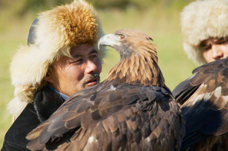 Almaty, Kazakhstan, September 18, 2011 - Portrait of Kazakh hunters holding golden eagles (Aquila...