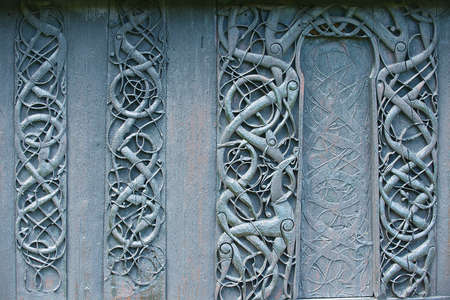 External wooden wall carved decoration of the medieval Urnes Stave church with viking motifs covered with tar in Ornes, Norway.の写真素材