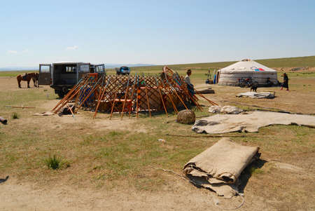 Kharkhorin, Mongolia, August 25, 2006 - Mongolian men assemble yurt (nomadic tent) in steppe in...