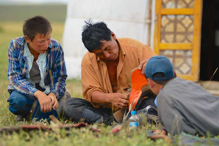 Kharkhorin, Mongoliab August 19, 2006 - Mongolian men fix traditional horse saddle in front of the yurt (nomadic tent) entrance circa Kharkhorin, Mongolia.のeditorial素材