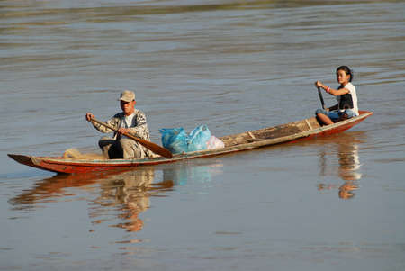 Luang Prabang, Laos, February 13, 2007 - People cross Mekong river by traditional long wooden boat near Luang Prabang, Laos.のeditorial素材