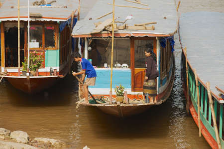 LUANG PRABANG, LAOS - APRIL 12, 2012: People park traditional long boats at the bank of the Mekong river in dry season in Luang Prabang, Laos.のeditorial素材