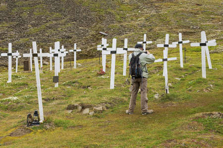LONGYEAARBYEN, NORWAY - SEPTEMBER 01, 2011: Man takes a photo of the white crosses at the cemetery in Longyearbyen, Norway.のeditorial素材