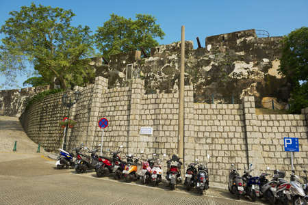 Macau, China - September 11, 2013: Exterior wall of the Guia Fortress with motorbikes parking at Caminho dos Artilheiros street in Macau, China.のeditorial素材