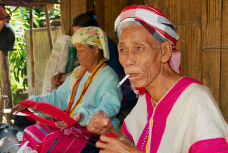 Doi Inthanon, Thailand - November 14, 2008: Unidentified senior people of the White Karen hill tribe weaving outside of their bamboo house in Doi Inthanon, Thailand.のeditorial素材