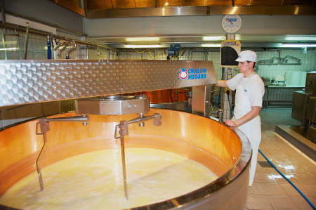 Gruyeres, Switzerland - December 11, 2009: Unidentified worker makes cheese at a cheese factory in Gruyeres, Switzerland.のeditorial素材